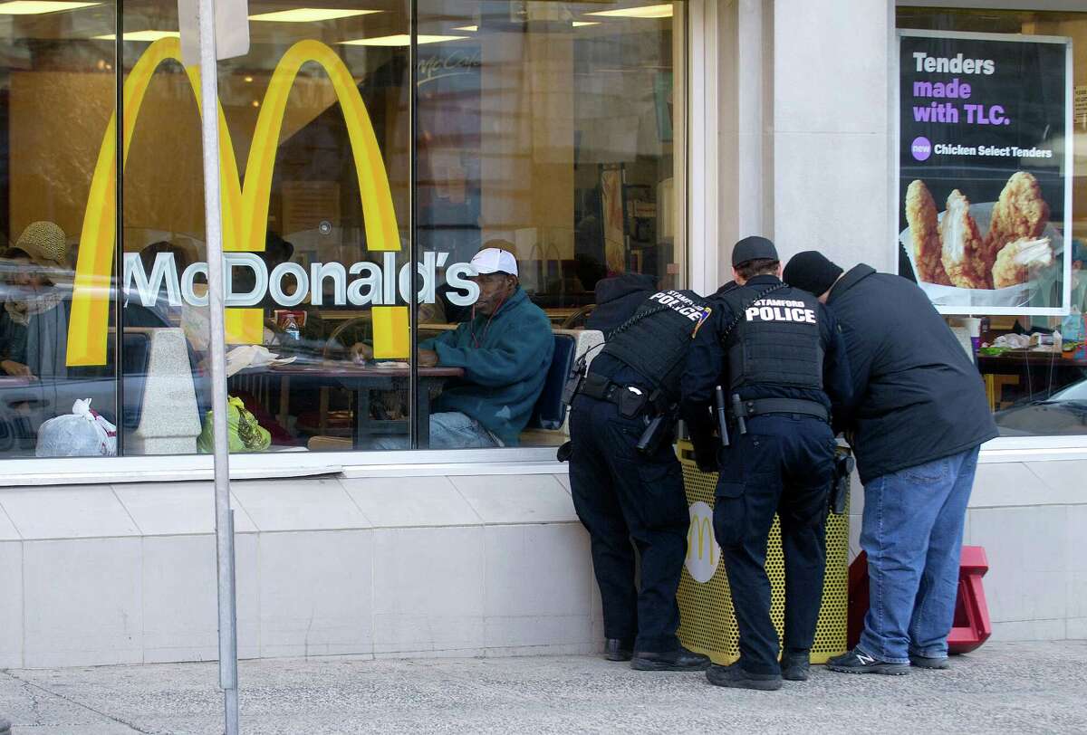 Stamford police officers search the trash bin outside McDonald's in Stamford, Conn., on Thursday, March 12, 2015, after Antonio Muralles was murdered after he was stabbed, beaten and robbed Wednesday night.