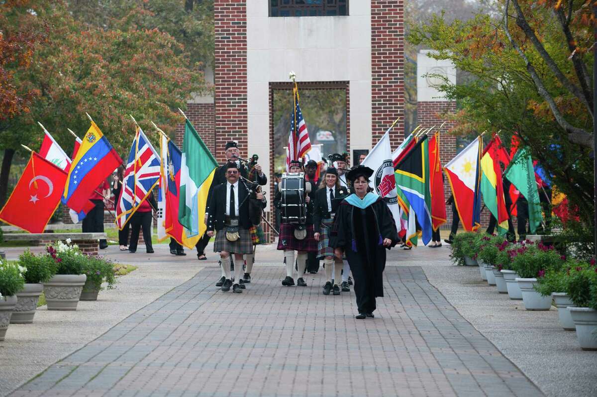 Registrar Dr. Bobbye Fry leads the graduation procession that includes the country flags of all graduates. Today, 19 percent of UIW students are international representing 70 countries.