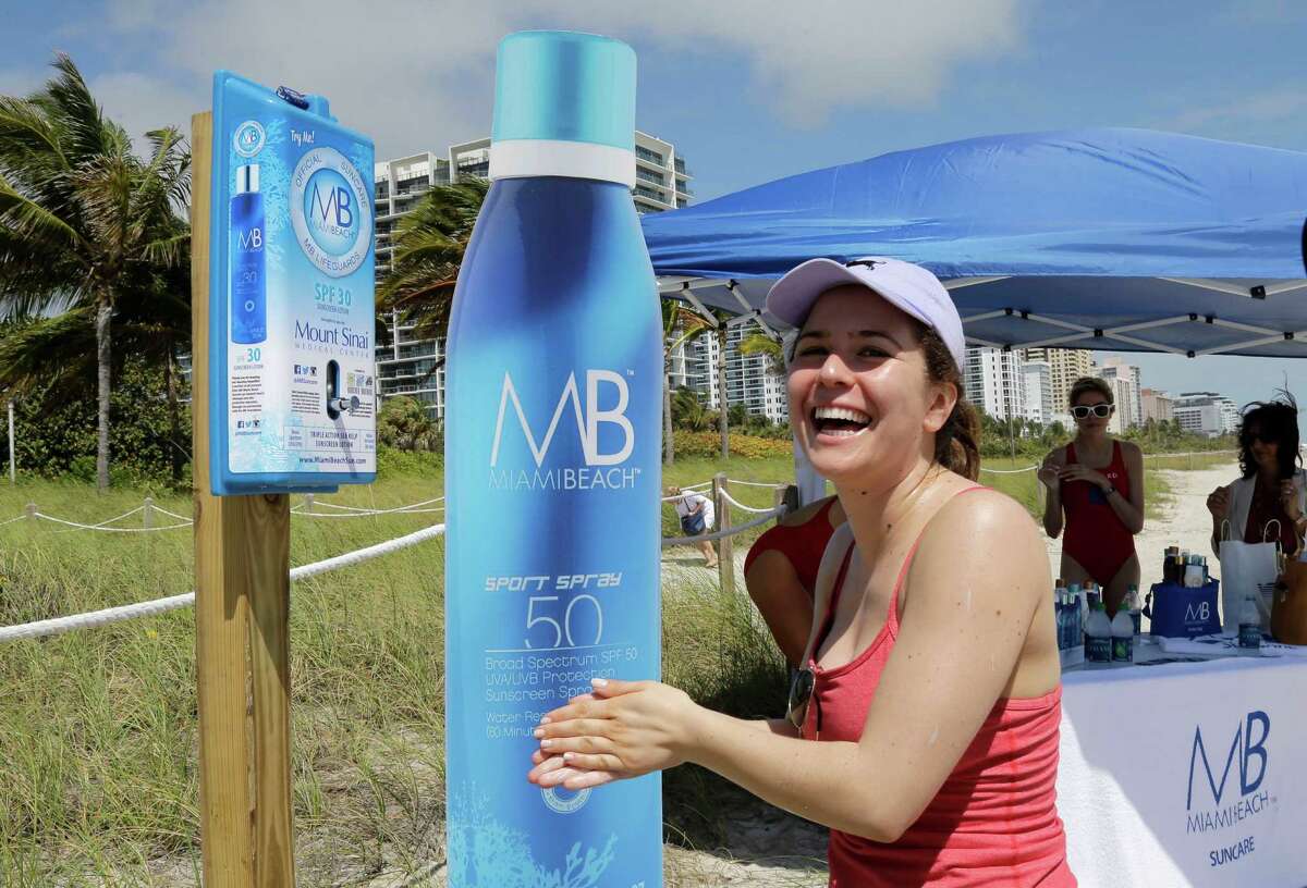 Rachel Gerber, of New York City, applies sunscreen at the beach, Friday, March 13, 2015, in Miami Beach, Fla. The City of Miami Beach is celebrating its centennial on March 26, installing 50 sunscreen dispensers throughout the city for public use as a birthday gift to the community. (AP Photo/Alan Diaz)