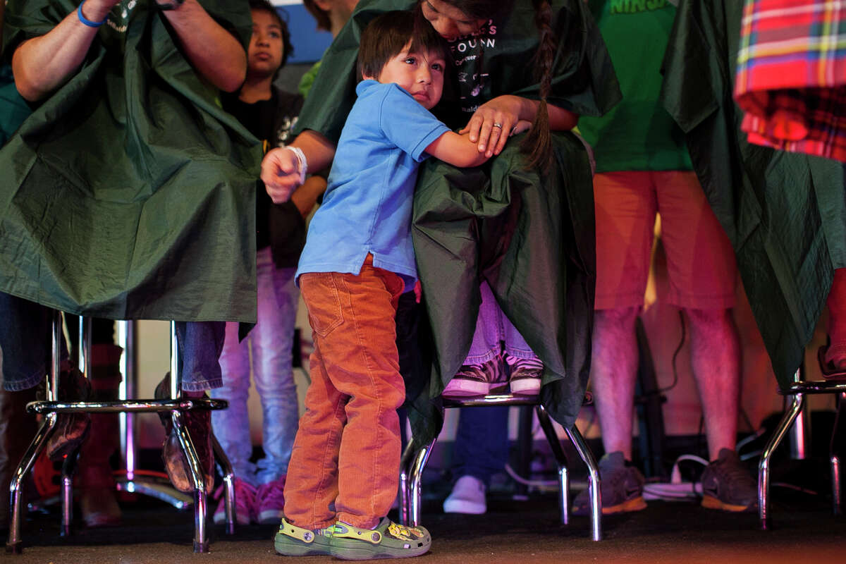 (Center) Sebastian Munoz, 4, stays by his mother's side while she shaves her head during St. Baldrick's Day today Saturday March 14, 2015 in San Antonio at World of Beer. Hundreds gathered from noon to 5 p.m. as monetary donations and "shavees" lined up to have their head shaved to raise money for childhood cancer research. This year they anticipated about 130 people to shave their heads, and hope to raise $100 thousand dollars for research.