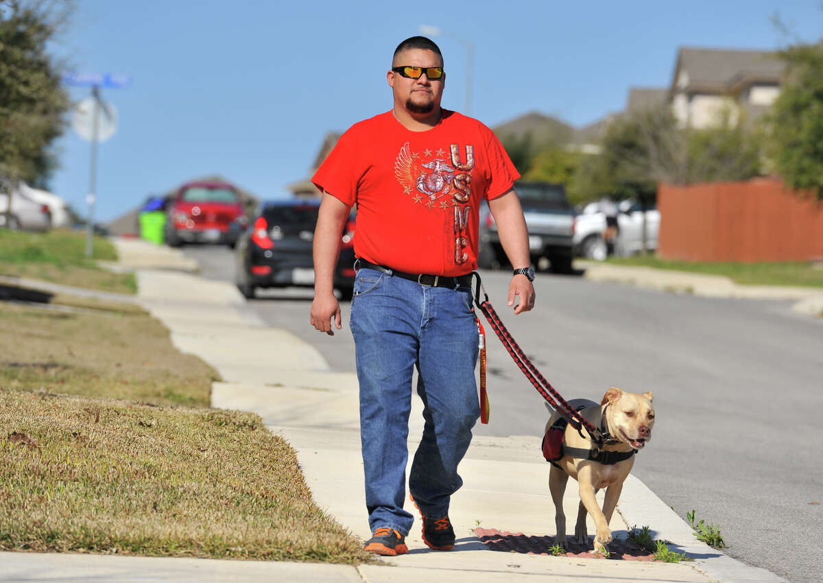 Juan Alonzo-Miranda walks with his service dog, Goldie, near their far West Side home.