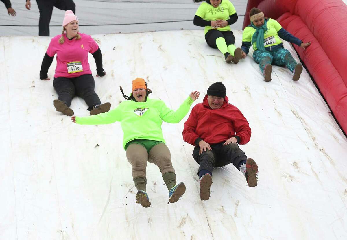 Helen Haby (center) and Charlie Neetz (right) join other participants bouncing their way down an inflated obstacle in the 5K ThrillSeeker Stunt Run at Wolff Stadium on Saturday, Feb. 28, 2015. Despite near freezing temperatures and early drizzle, people still took part in the event which featured several challenging yet fun obstacles along a route. (Kin Man Hui/San Antonio Express-News)