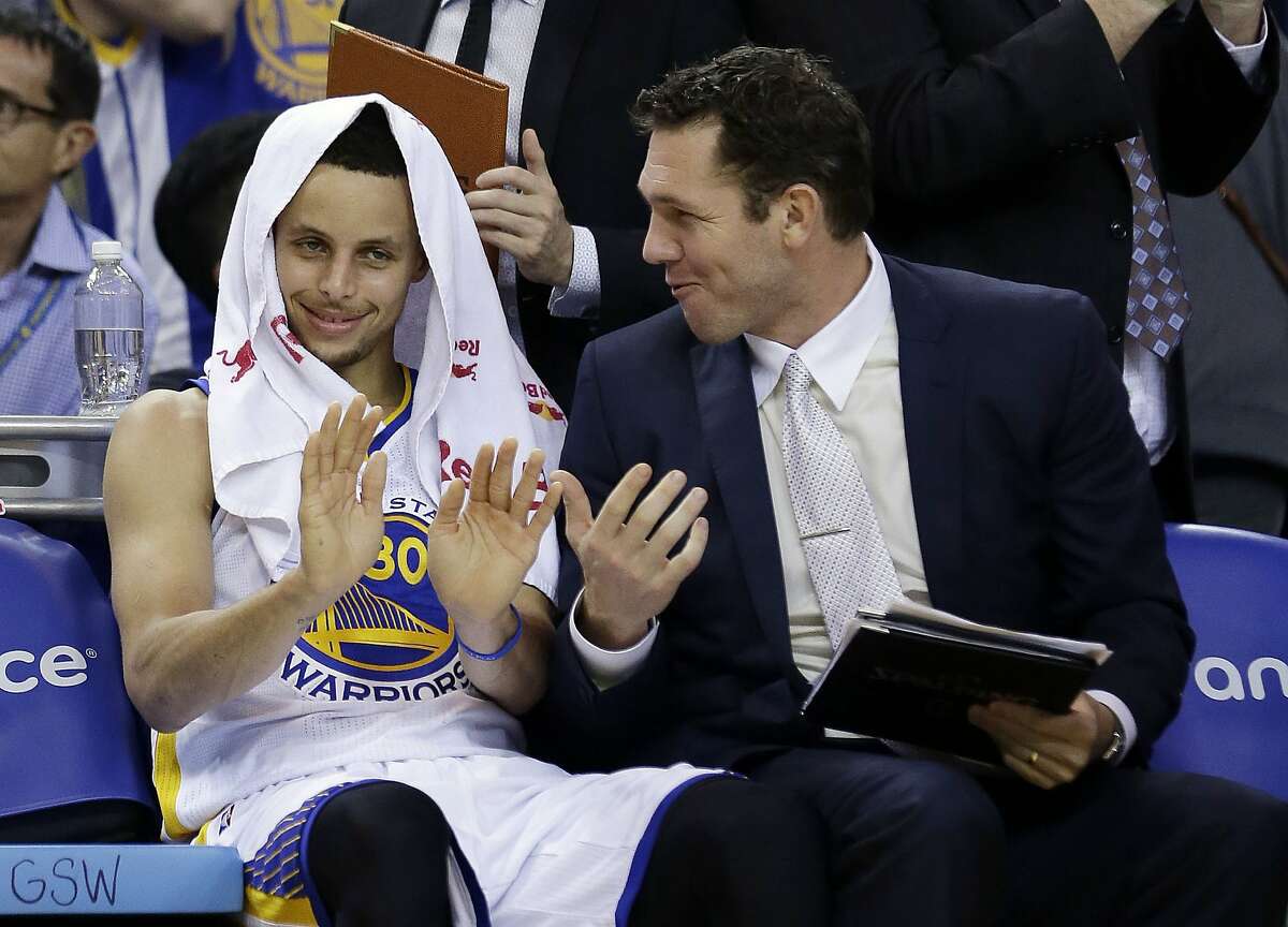 Golden State Warriors' Stephen Curry, left, jokes with assistant coach Luke Walton after a dunk from teammate Andre Iguodala during the second half of an NBA basketball game against the New Orleans Pelicans, Friday, March 20, 2015, in Oakland, Calif. (AP Photo/Marcio Jose Sanchez)