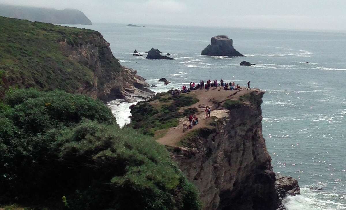 Five hours before a cliff gave way Saturday, killing one hiker and injuring another at Point Reyes National Seashore, Karen Blasing snapped a photo of dozens of people who ventured past warning signs to the bluff overlooking Arch Rock. “It was clear no one should be on that rock with the huge fissure,” she said.