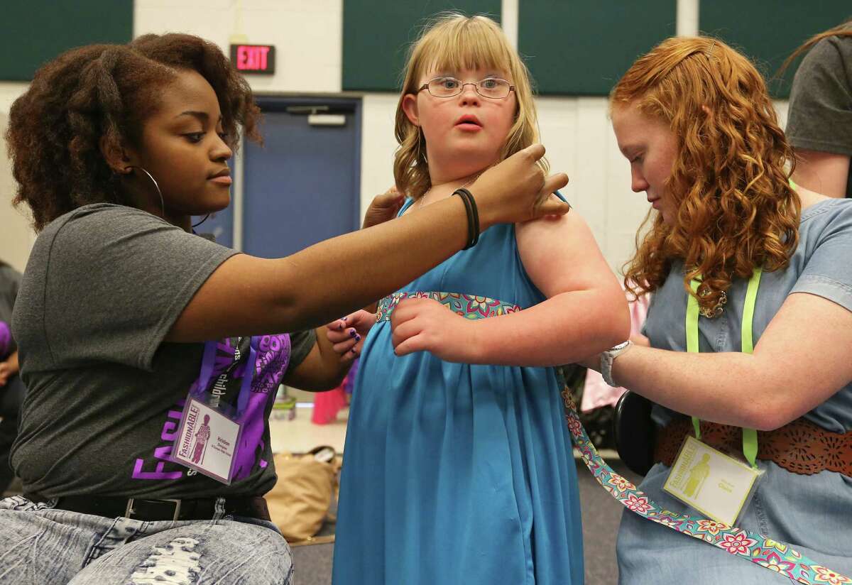 Designer O'Connor high school senior Kristian Williams, 17, (from left) adjusts model Evers elementary 5th grader Claire Graham, 10, outfit as Claire's sister Warren high school's Abbey Graham, 16, helps during the 8th annual FashionAble show held Sunday March 22, 2015 at O'Connor High School.