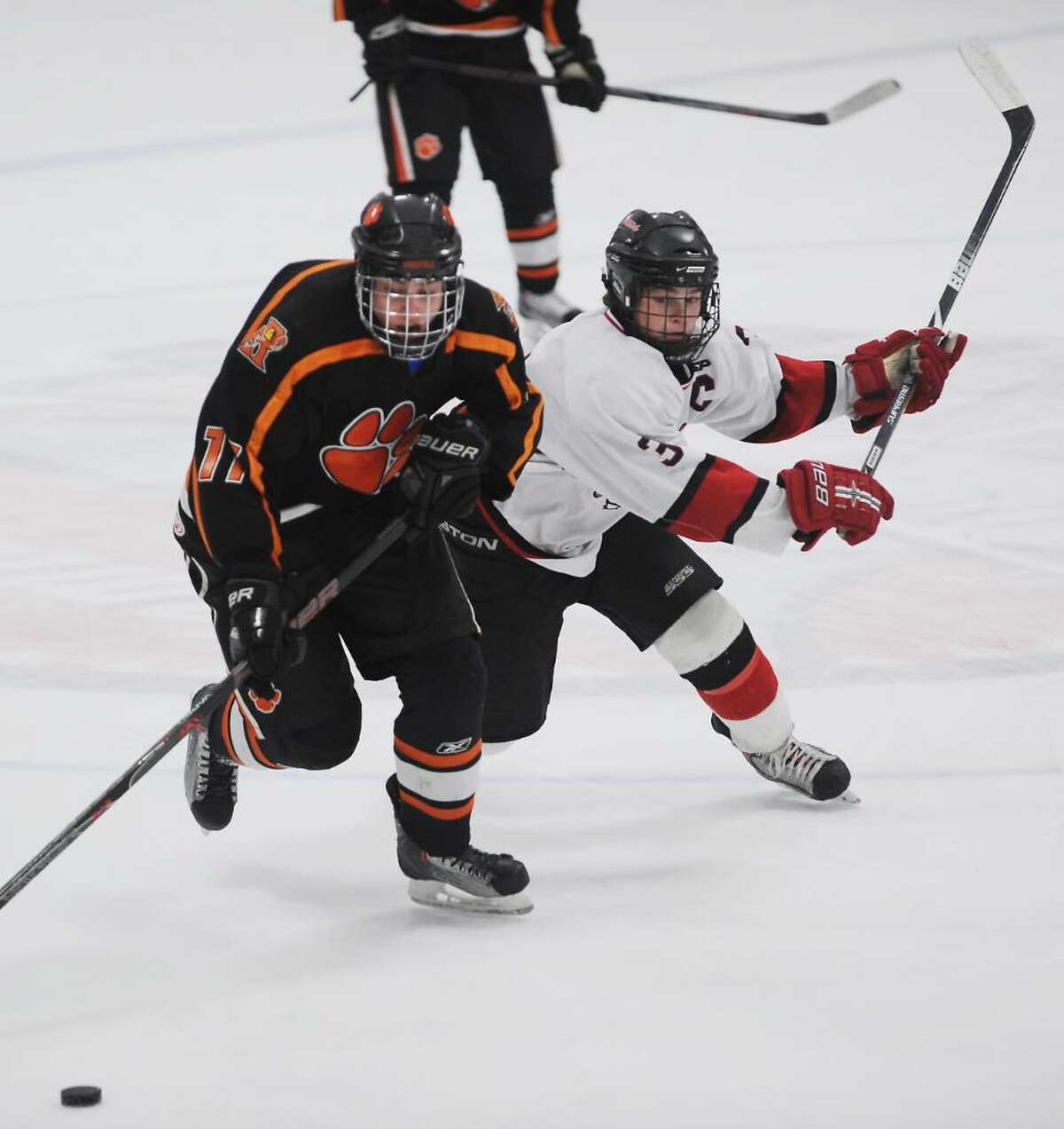Ridgefield's Chas South is pressured by New Canaan's Andrew Leslie in the FCIAC boys hockey championship game at Terry Conners Rink in Stamford, Conn. on Saturday, March 6, 2010.