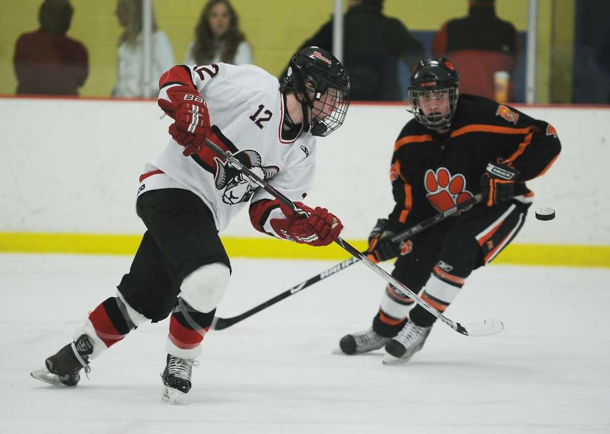 New Canaan's Tim Robustelli passes the puck against Ridgefield's Danny McMullan in the FCIAC boys hockey championship game at Terry Conners Rink in Stamford, Conn. on Saturday, March 6, 2010.