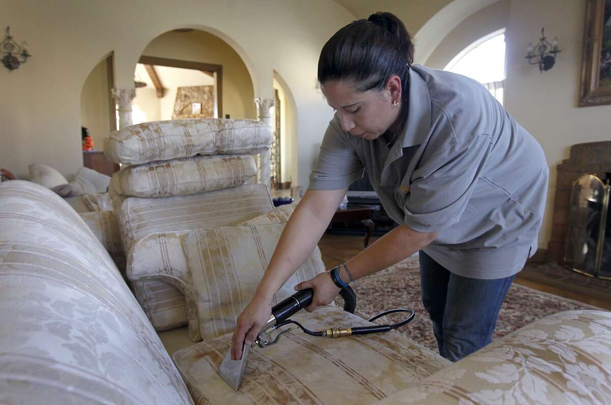 Rosa Sanchez, of Homejoy, cleans a sofa for Rie Yamazaki-Bach in San Francisco, Calif. on Tuesday, Oct. 28, 2014. Many homeowners are turning to Homejoy to connect with maintenance services such as carpet cleaning, plumbing and painting.