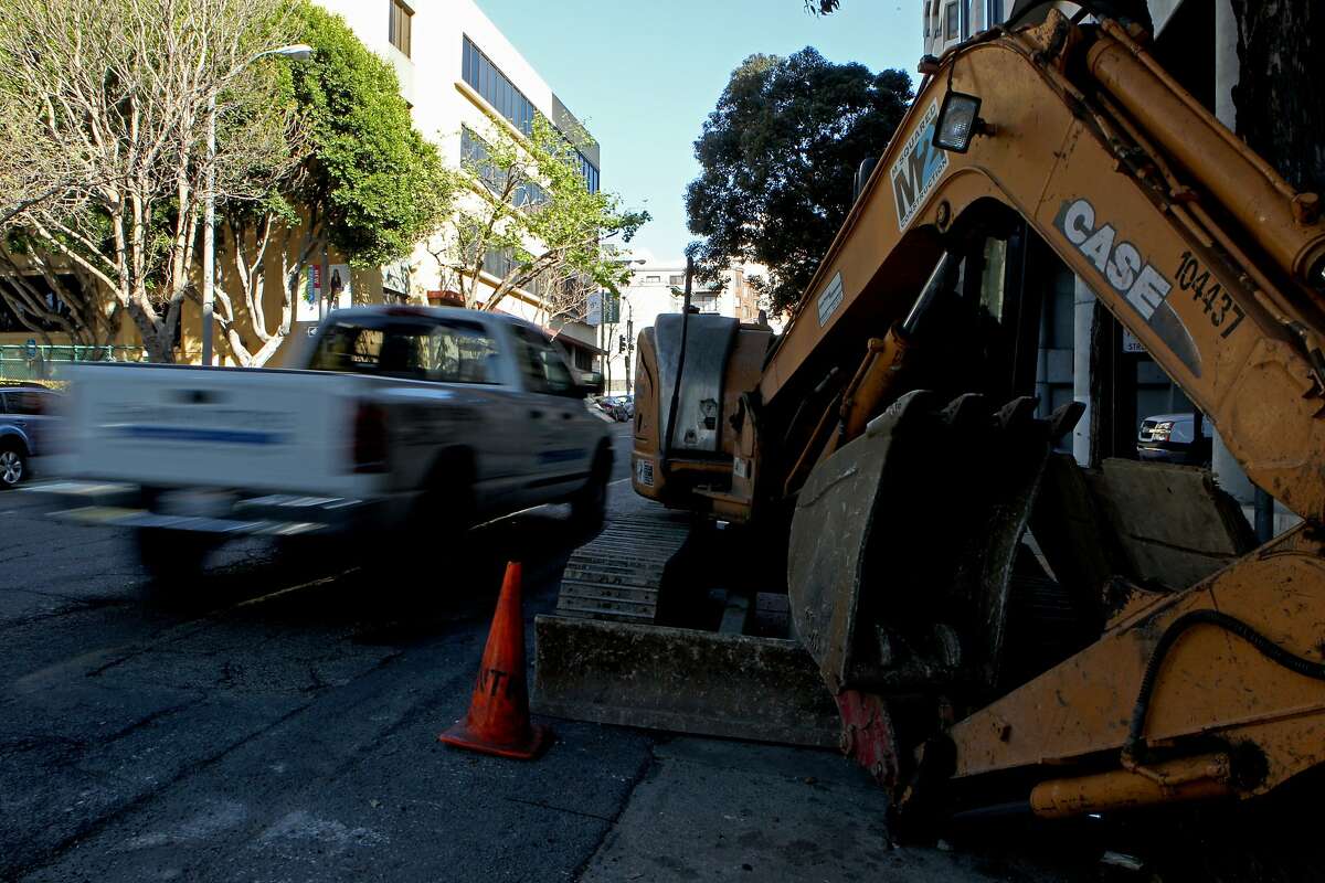 An excavator construction vehicle is parked near the area where motorists are driving over cracks and potholes at Golden Gate Avenue along Franklin Street, Wednesday, March 18, 2015, in San Francisco, Calif. The roads are heavy with damage along Franklin and Gough streets giving motorists a bumpy ride.