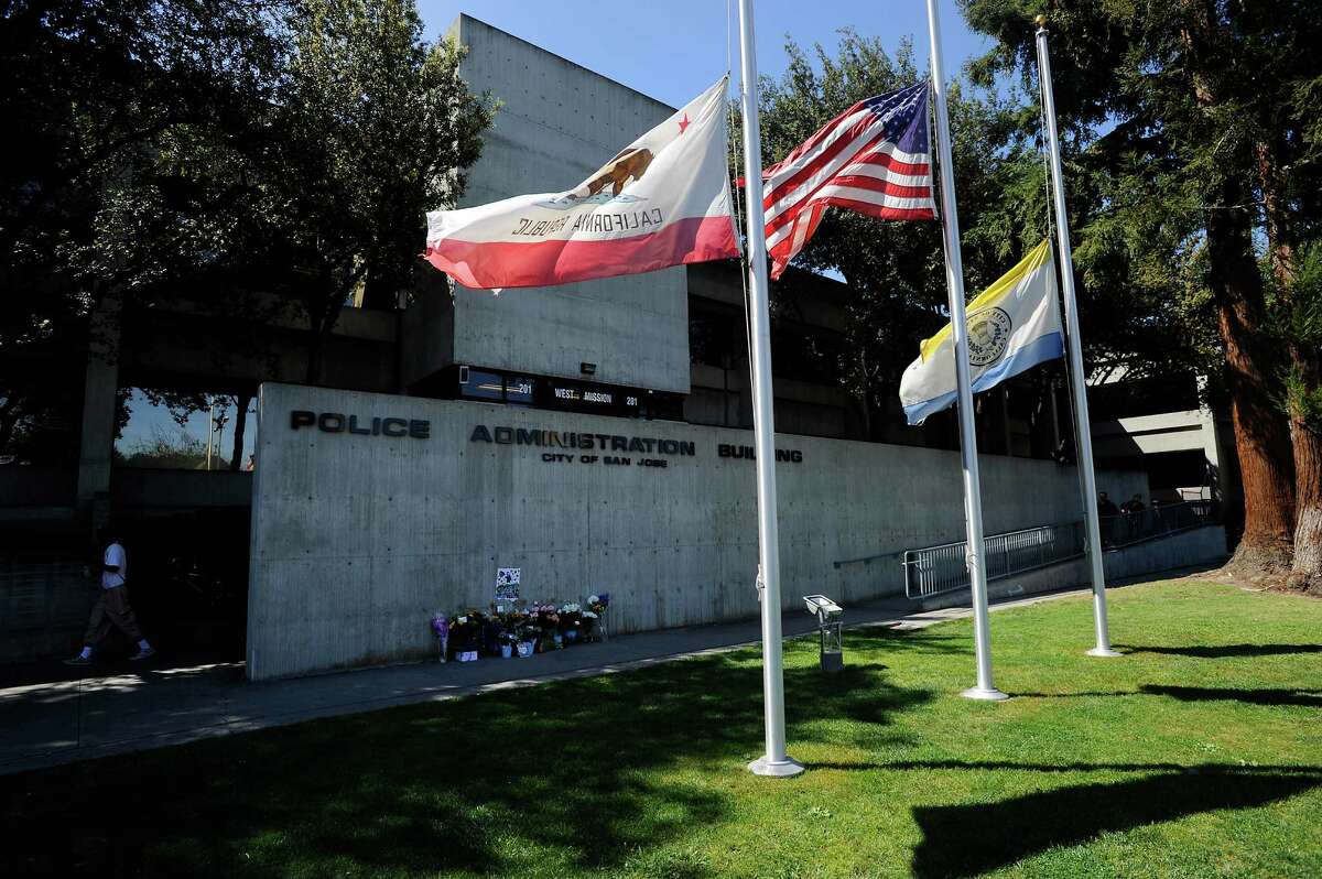 Flags file at half-staff next to a memorial for slain police Officer Michael Johnson in front of the San Jose Police Department headquarters.