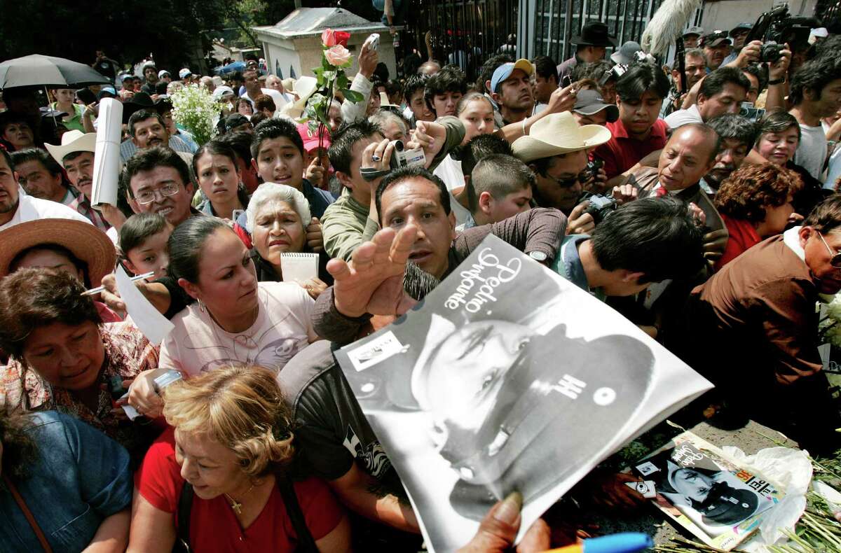 A man tries to reach an image of Pedro Infante at his grave in Mexico City, Sunday, April 15, 2007. Thousands of Mexicans visited the gravesite of the legendary actor and singer, who was killed 50 years ago in a plane crash in Merida, Mexico.