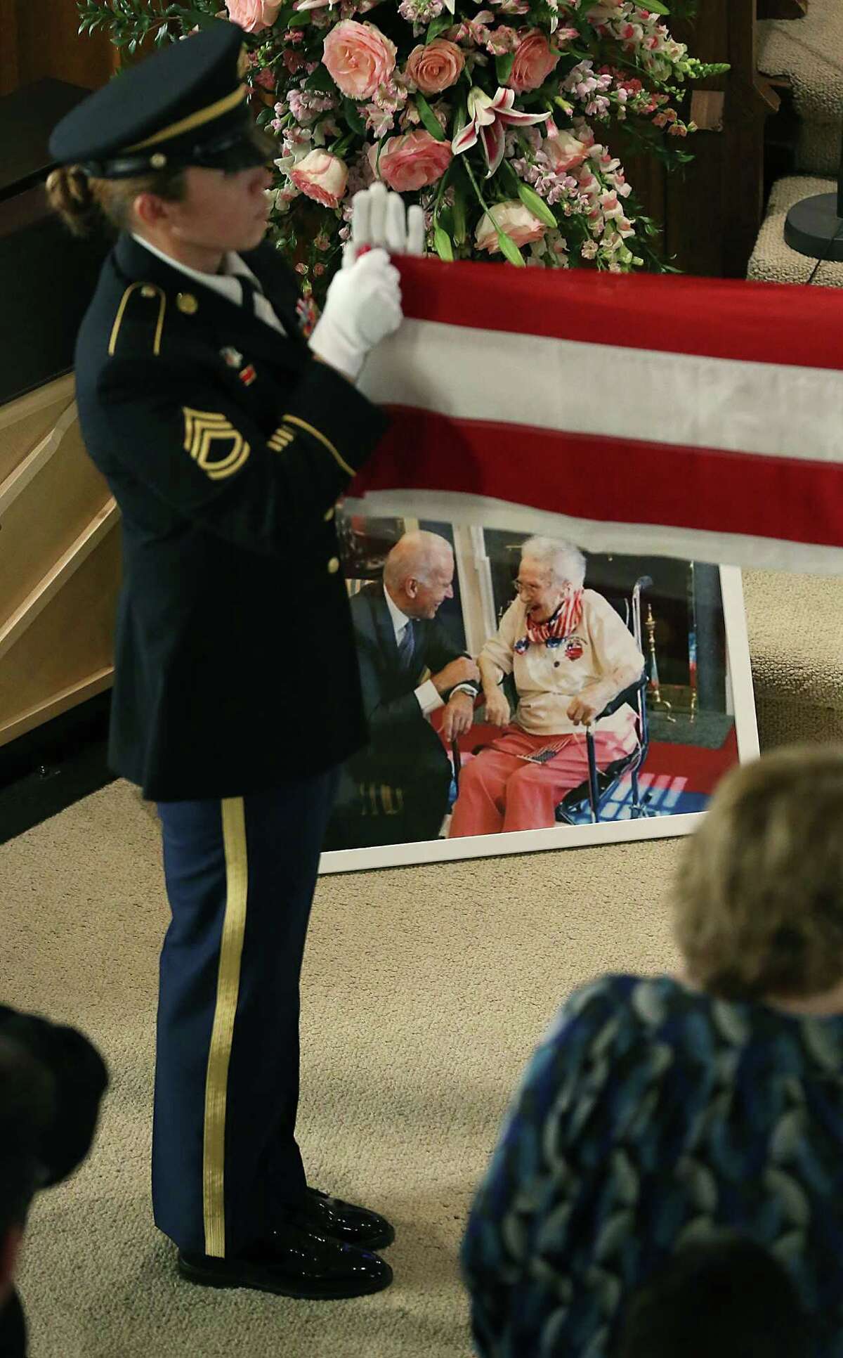 RIGHT: A Fort Sam Houston honor guard member folds a flag next to a photo of Coffey with Vice President Joe Biden during her memorial service at Madison Square Presbyterian Church.