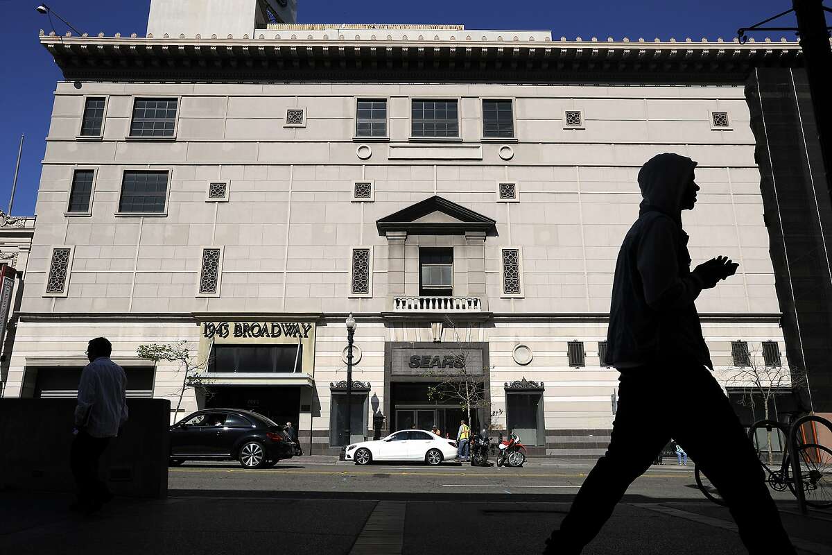 People walk past the Sears building in downtown Oakland, CA, on Thursday, March 26, 2015. Construction on the Uptown Station project is underway at the old Sears building on 20th Street and Broadway in downtown Oakland.