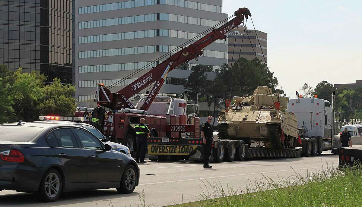 A Houston Police Officer directs traffic as workers prepare to reload an armored military vehicle on to a trailer after the vehicle shifted on the trailer on IH 610 North just west of Shepherd Thursday, March 26, 2015, in Houston.