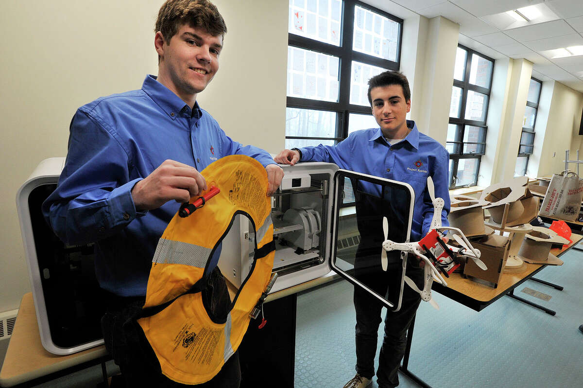 King School seniors Nick Smith, left, and Thomas Catenacci pose next to the school's 3D printer where they created a part that would allow a drone to quickly deliver a life preserver to a drowing victim at King School in Stamford, Conn., on Thursday, March 26, 2015. Students at King School started a venture titled Project Ryptide with Flying Robots owner Bill Piedra. The partnership resulted in an attachment for a DJI Phantom drone, a popular unmanned aerial vehicle, that would enable the quadcopter to deliver an inflatable life ring to victims far out to sea.