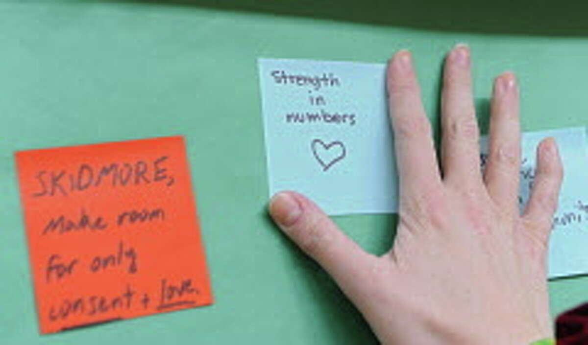 A student puts a sticky note on a wall during a silent rally to protest a college readmission hearing for a male student who was suspended for a year for sexually assaulting Skidmore College student Reina Keifer at Skidmore College on Friday, March 13, 2015 in Saratoga Springs, N.Y. (Lori Van Buren / Times Union)