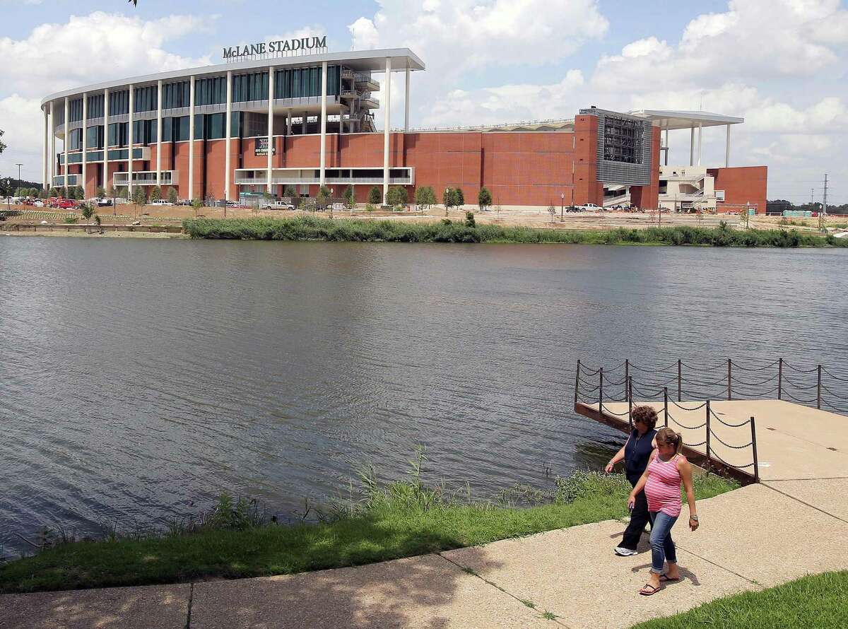 FILE - In this July 2, 2014, file photo, people stroll along the river walk across from the new McClane Stadium at Baylor University in Waco, Texas. The $260 million stadium located near campus on the Brazos river debuts at the end of the month and replaces the 64-year-old Floyd Casey Stadium. (AP Photo/Waco Tribune Herald, Jerry Larson, File)
