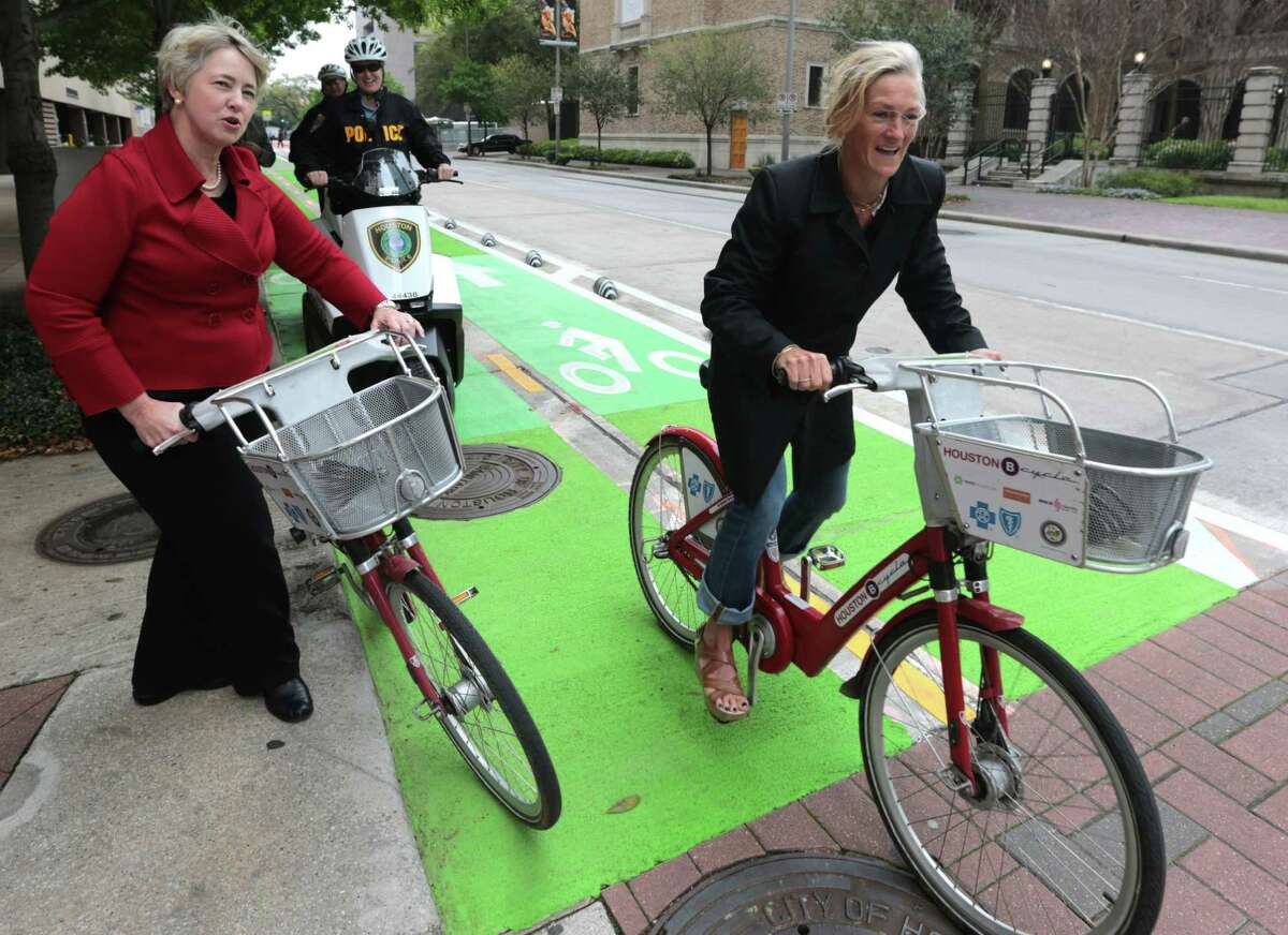 (left) Houston Mayor Annise Parker cheers on a bike rider during the opening of the new downtown park connector. Houston Mayor Annise Parker and other city and state dignitaries gathered to open the Lamar bike lane Thursday March 26, 2015. Houston construction crews have been working on the two-way cycle track on Lamar for the past ten weekends. The lane is ten blocks long located at Lamar Street at Brazos between Bagby and Smith, near the Houston Public Library. but will help connect other major trails.