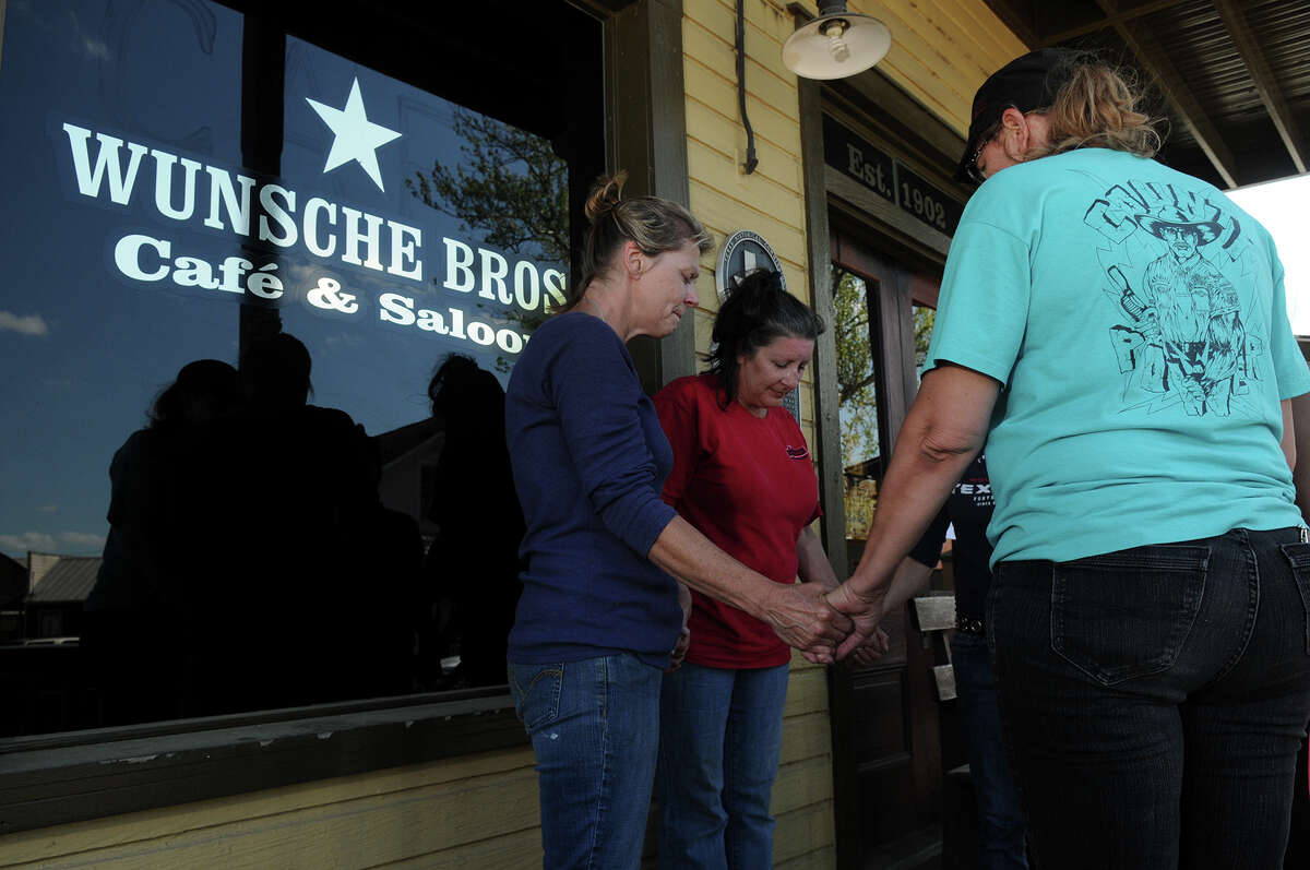 Wunsche Bros. Cafe and Saloon employees, including Beth Vincent, from left, Kathleen O'Brien, Kim Mitchell, Debra Kelly, and former employee Sarah Herrera gather for a prayer Sunday afternoon at the front entrance to the restaurant in Old Town Spring which was damaged by fire early Sunday morning.