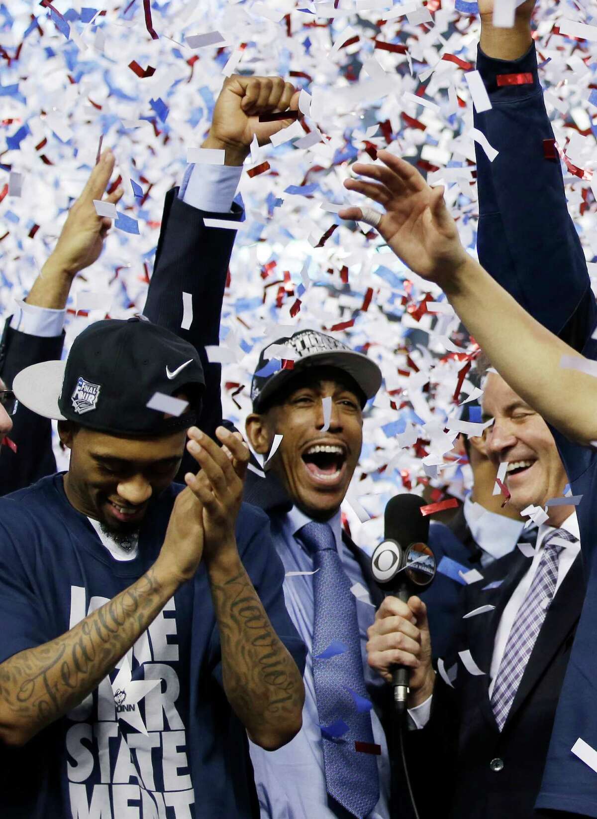 Connecticut player Ryan Boatright and head coach Kevin Ollie, center, celebrates with his team after their 60-54 victory over Kentucky in the NCAA Final Four tournament college basketball championship game Monday, April 7, 2014, in Arlington, Texas.
