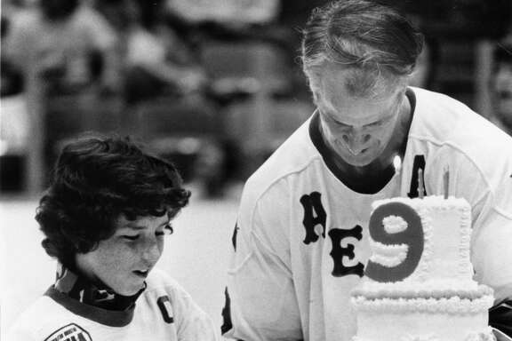 04/06/1976 - Kevin Dineen, left, son of Houston Aeros coach Bill Dineen, lends a helping hand to Gordie Howe during ceremonies between periods Tuesday night at The Summit. The crowd of 12,091 sang happy birthday to the 48-year-old star, who celebrated the event by scoring a goal and assisting on two others as the Aeros defeated Phoenix, 8-5, assuring the defending Avco World Trophy champions home-ice advantage in the upcoming World Hockey Association playoffs.