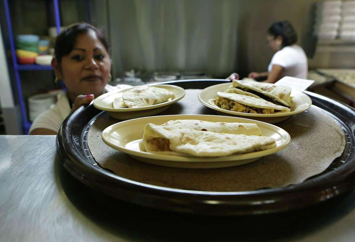 Rosa's Tacos To Go really brings it with the chicharron taco. Here, Esmeralda Ruiz puts up a finished order of tacos.