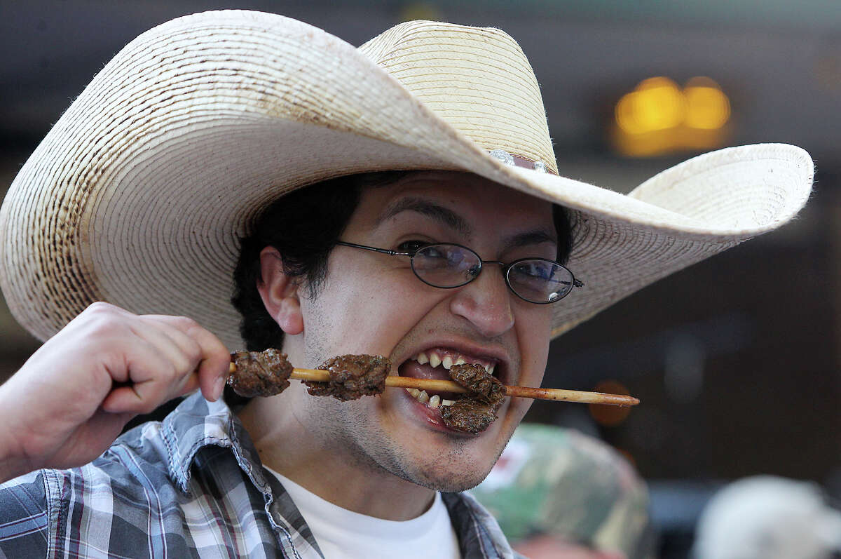 Antonio Guerreo wears a big hat while he takes a big bite from his skewer of anticuchos on the first night of a Night in Old San Antonio on Apr. 24, 2012.