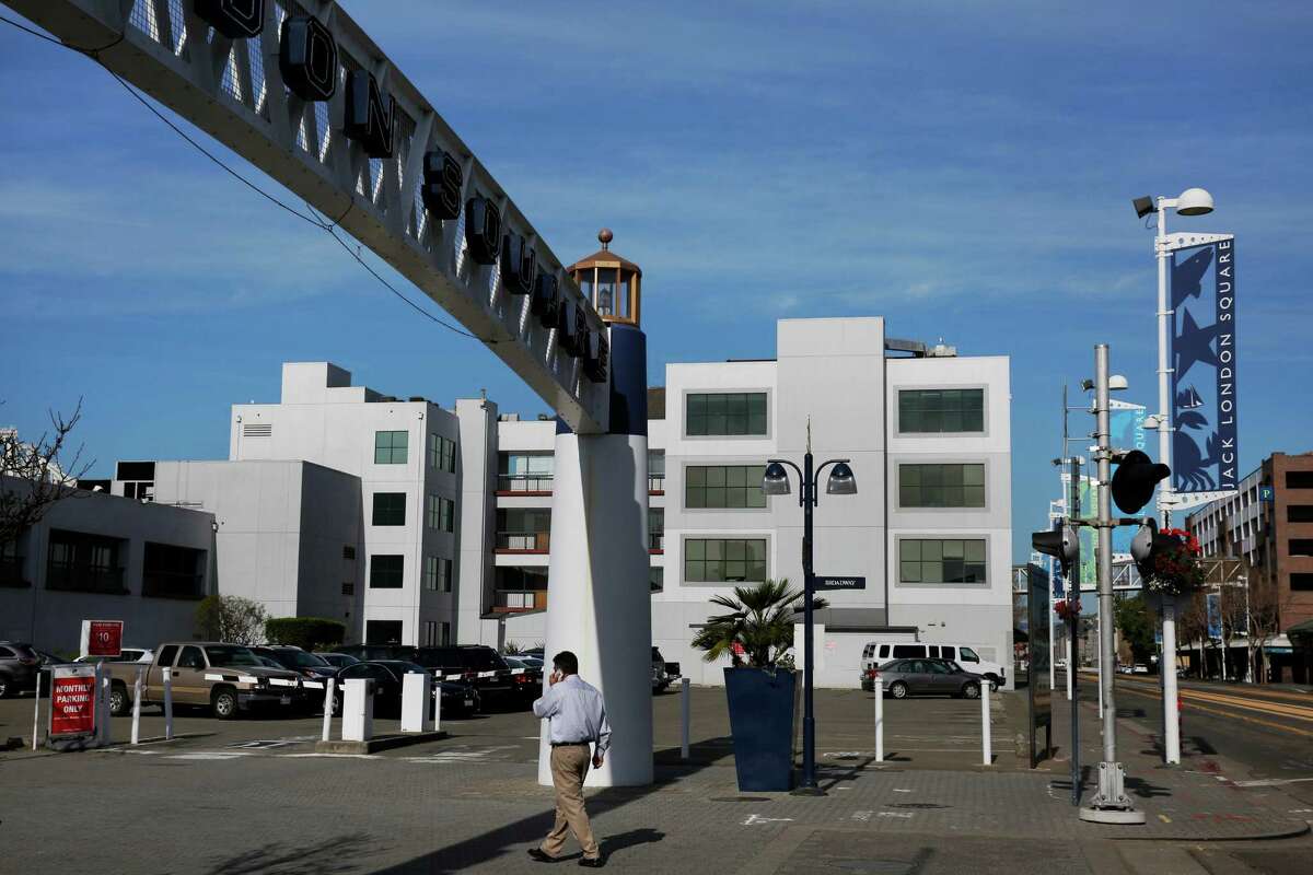 A pedestrian walks past a parking lot on Embarcadero West and Broadway that is slated to be the location of new housing March 17, 2015 in Oakland, Calif.
