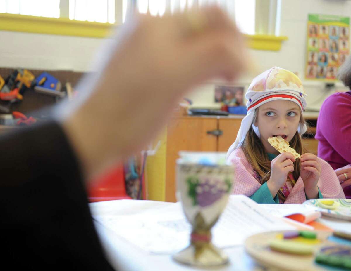 Four-year-old Sally Pelligra eats matzoh as she learns about Passover from Rabbi Colin Brodie Thursday, April 2, 2015, during a model seder at Congregation B'Nai Torah in Trumbull, Conn.