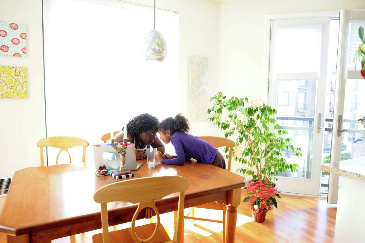 Sisters Olive (left), 15, and Carter, 6, hang out at the dinning table of their apartment in the Uptown area of Oakland, a place their mother loves living in but wishes it had more community spaces to gather.