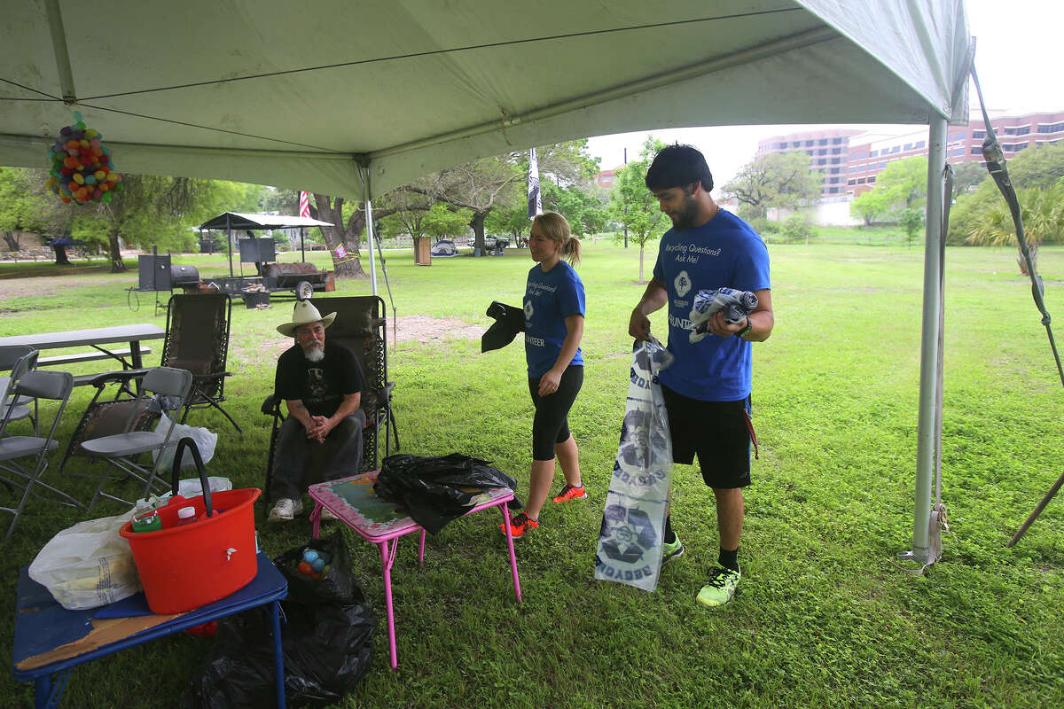 Volunteers Nikki Merrill (center) and A.J. Martinez (right) deliver free trash and recycle bags Friday April 3, 2015 to the camp site of Danny Garza (seated) at Brackenridge Park before Easter weekend. Merrill and Martinez are U.T.S.A. students and volnteered to work for the city to help keep the park clean.