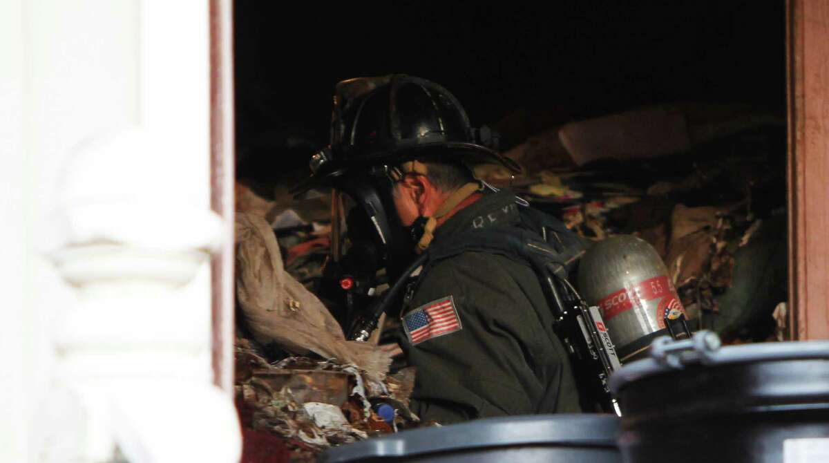 Firefighters search among mounds of trash inside a home where a body was reportedly dead inside near 4th and Lake Street in the Richmond District of San Francisco, Calif. Saturday, April 4, 2015.