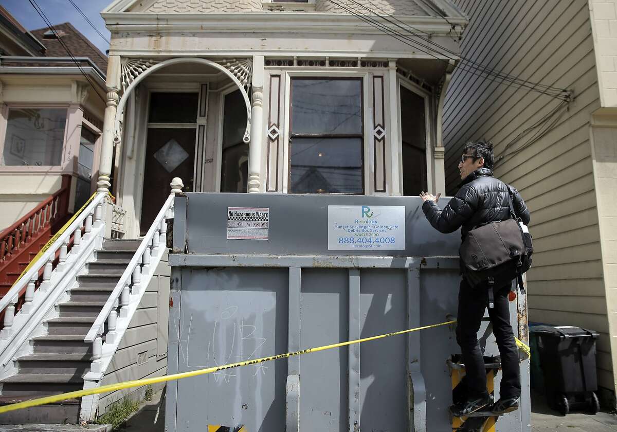 San Francisco Supervisor Eric Mar tries to look into a dumpster as he checked in with neighbors on Sunday, April 5, 2015 at the home in San Francisco , Calif. where a mummified body had been discovered the day before. Mar was looking for comments from neighbors on how the city could prevent the spread of vermin and spiders as the home is emptied and to provide services for mental health or senior care to stop such a thing from happening to other elders.