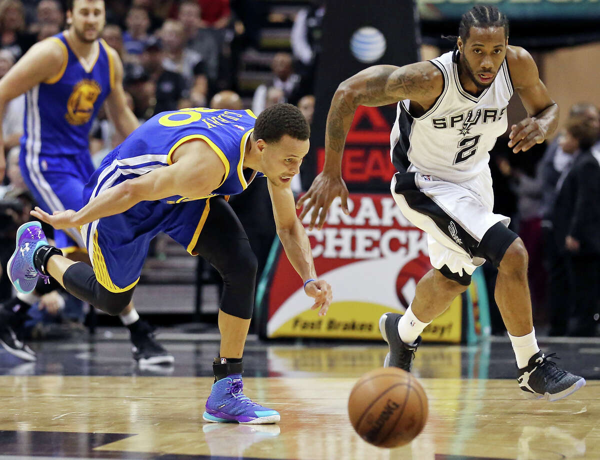 Golden State Warriors’ Stephen Curry and Spurs’ Kawhi Leonard chase after a loose ball during first half action on April 5, 2015 at the AT&T Center.