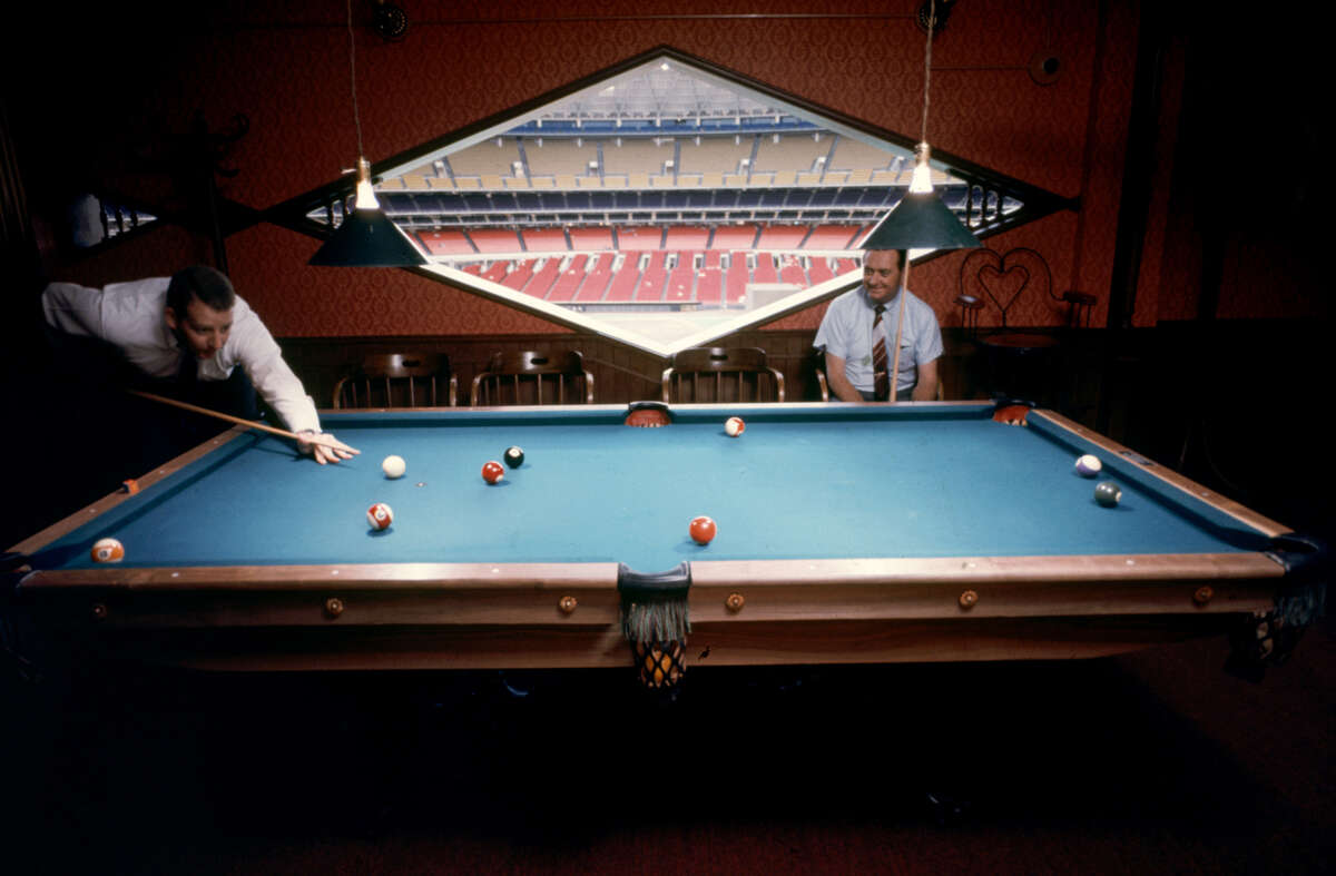 A pair of unidentified men as they play billiards in one of the private 'sky rooms' in the Astrodome, Houston, Texas, June 1968. The field and grandstands are visible though the diamand-shaped window at center.