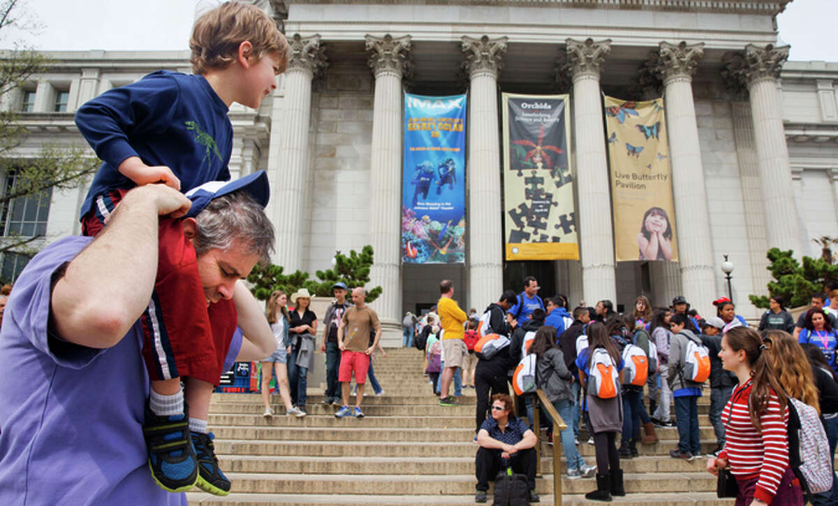 Chris Cellini of Charlotte, N.C., left, lifts his son Aiden Cellini, 5, onto his shoulders after a visit to the Natural History Museum on the National Mall in Washington, Tuesday, April 7, 2015. Widespread power outages affected the White House, State Department, Capitol and other sites across Washington and its suburbs Tuesday afternoon — all because of an explosion at a power plant in southern Maryland, an official said.
