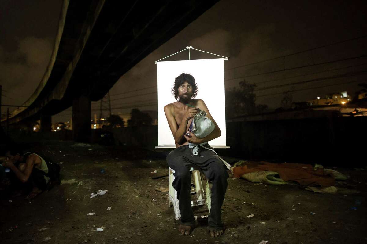 In this March 17, 2015 photo, Renato Dias, 39, writes in his notebook as he poses for a portrait in an open-air crack cocaine market, known as a “cracolandia” or crackland, where users can buy crack, and smoke it in plain sight, day or night, in Rio de Janeiro, Brazil. Dias, who has been using crack for about 4 years, says he uses his notebook as a form of distraction. He writes about super heroes and dreams of becoming one. (AP Photo/Felipe Dana)