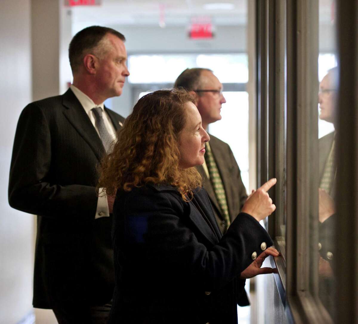 Paul Fonteyne, President and CEO of BIUSA, left, and James Baxter, Senior VP of Development, R&D, with U.S. Representative Elizabeth Esty, 5th District of Connecticut, during a tour of the Boehringer Ingelheim USA Corporation pilot research building at their Danbury, Conn, campus on Wednesday, April 8, 2015. They are looking through windows into a robotics lab.