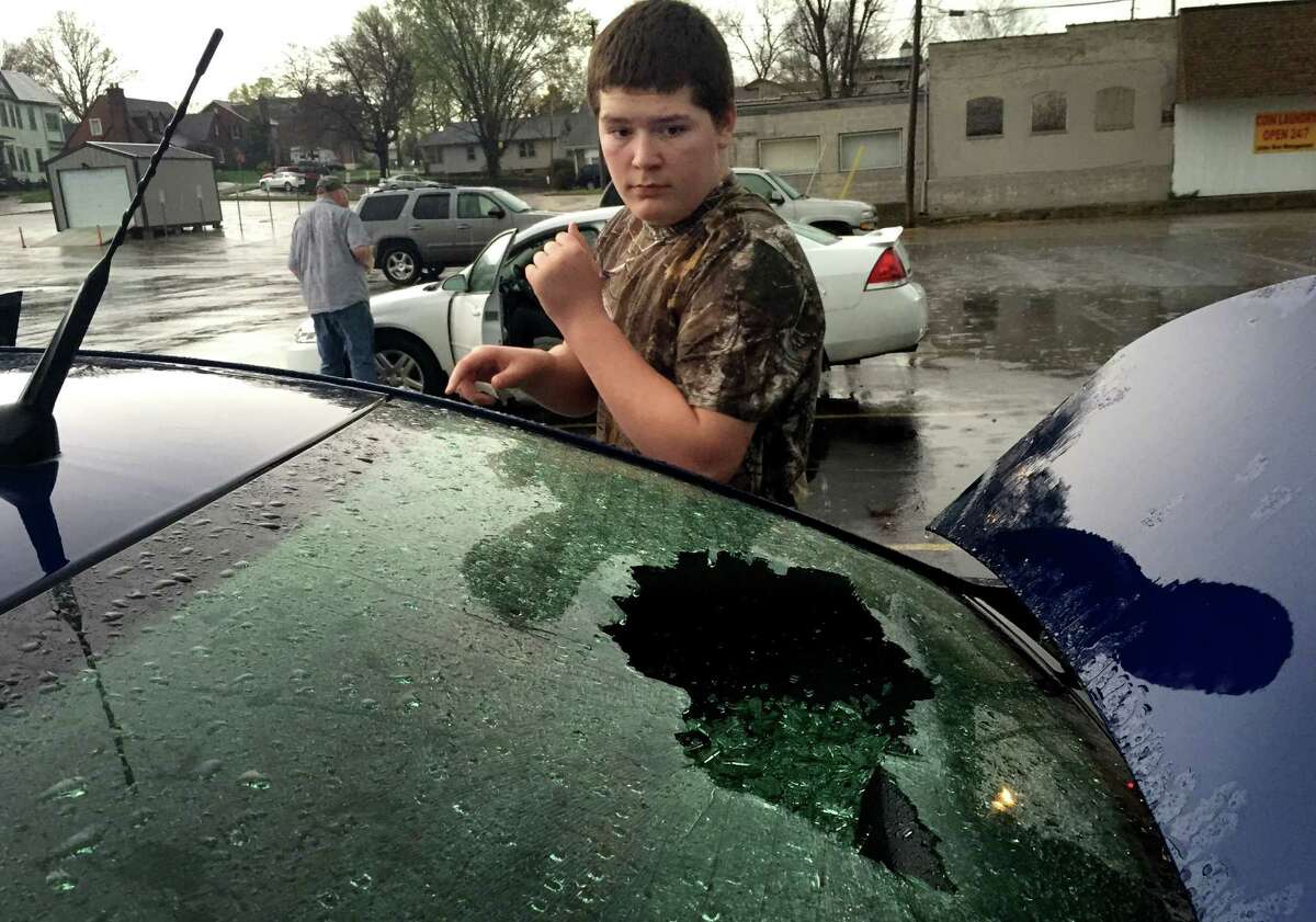 Derek Smith, 14, from Bonne Terre, looks at the shattered rear window of his mom's car that was busted out by hail slightly smaller than a tennis ball that fell from a storm in downtown Farmington, Mo., Wednesday, April 8, 2015. Numerous cars sustained broken windows from the hail. EDWARDSVILLE INTELLIGENCER OUT, THE ALTON TELEGRAPH OUT