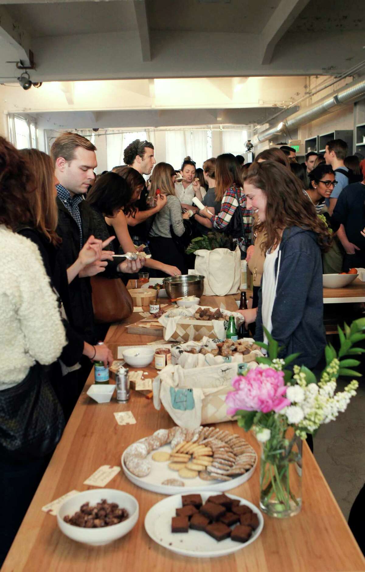Customers socialize and sample Good Eggs snacks at the monthly open studio event at Everlane's office.