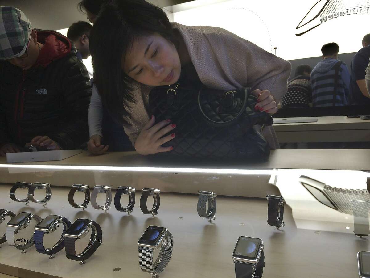 A customer takes a close look at Apple Watches on display in a glass case at an Apple retail store in Beijing, Friday, April 10, 2015. From Beijing to Paris to San Francisco, the Apple Watch made its debut Friday. Customers were invited to try them on in stores and order them online. China was among countries where the watch had its global debut Friday, reflecting the country's fast-growing status as one of Apple's most important markets. (AP Photo/Ng Han Guan)
