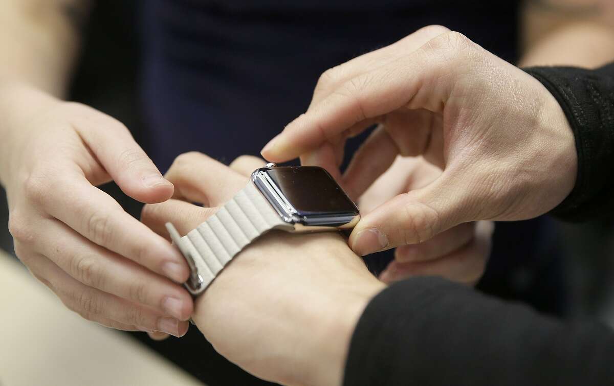 A customer tries on Apple's new watch at a store in San Francisco, Friday, April 10, 2015. Apple has started taking orders for the watch on its website and the Apple Store app. Currently, that's the only way Apple is selling the watch, with shipments scheduled to start April 24. (AP Photo/Eric Risberg)