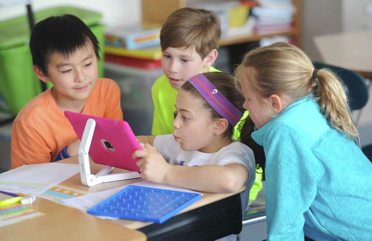 Fourth-graders, from left, Ibuki Matsushita, Will Duncan, Tori Ware and Logan Gilbrid use an iPad for a math project at North Mianus School in Greenwich, Conn. Wednesday, April 1, 2015. With the advances of technology in the classroom, students and teachers are balancing digital learning on platforms like the iPad with traditional pen and paper, non-digital resources.