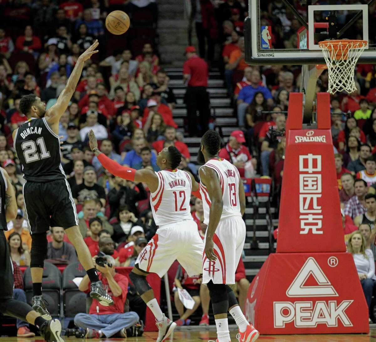 San Antonio Spurs forward Tim Duncan (21) shoots over Houston Rockets center Dwight Howard (12) as guard James Harden (13) looks on during the first half of an NBA basketball game Friday, April 10, 2015, in Houston.