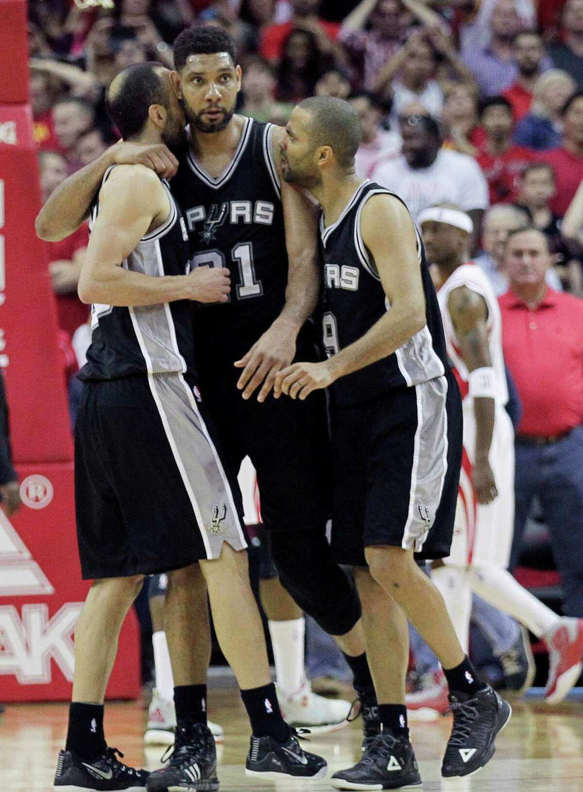 San Antonio Spurs forward Tim Duncan (center) receives a hug from Manu Ginobili (left) and Tony Parker after Duncan blocked a layup attempt by Houston Rockets guard James Harden at the buzzer during the second half on April 10, 2015, in Houston.