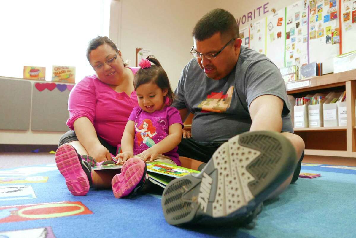 Emma Guzman, 2, reads a book with the help of her parents, Andrew and Jennifer Guzman, at the San Antonio Book Festival at the Southwest School of Art and the Central Library on April 11, 2015. The 2016 event will be April 6.
