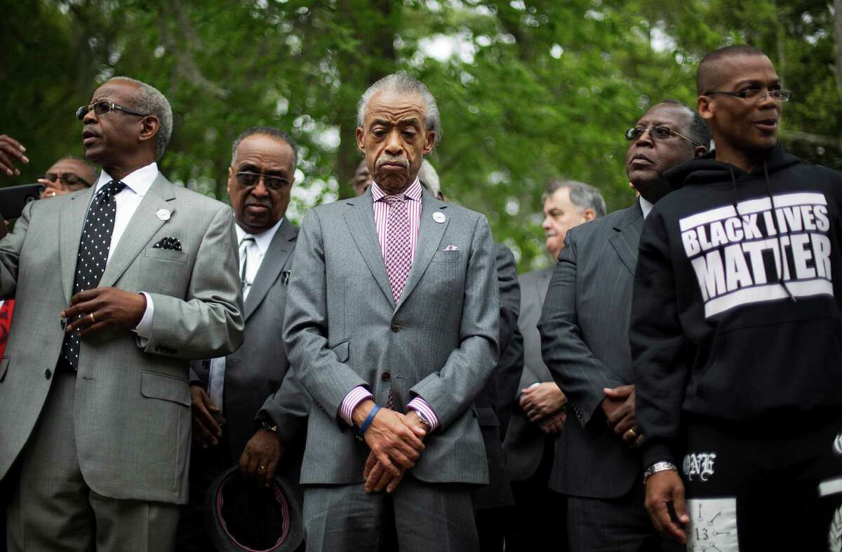 The Rev. Al Sharpton, center, visits a makeshift memorial where Walter Scott was fatally shot by a white police officer after he fled a traffic stop, Sunday, April 12, 2015, in North Charleston, S.C. The officer, Michael Thomas Slager, has been fired and charged with murder. (AP Photo/David Goldman)