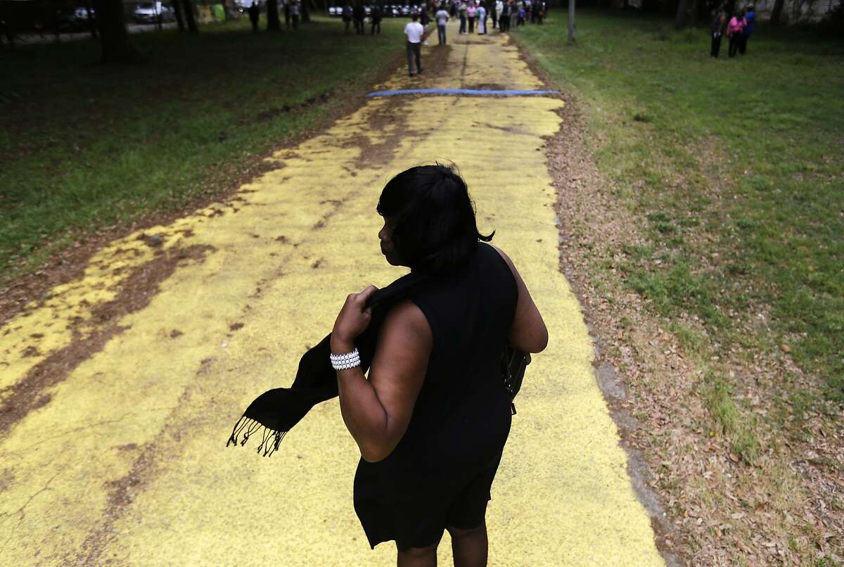 Laverne Taylor, of North Charleston, S.C., adjusts her scarf while walking to visit the scene where Walter Scott was fatally shot by a white police officer after he fled a traffic stop, Sunday, April 12, 2015, in North Charleston, S.C. The officer, Michael Thomas Slager, has been fired and charged with murder.