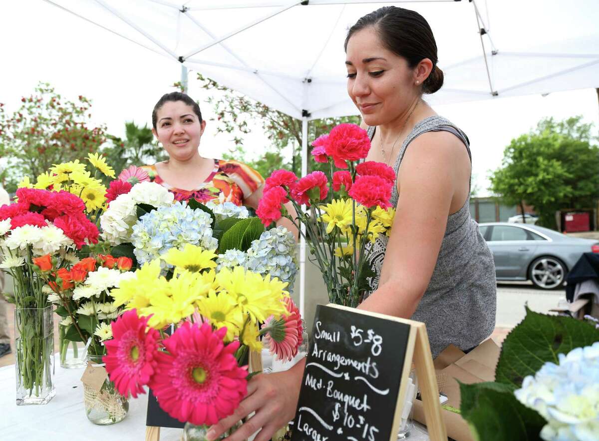 Carolina Alvarez, right, sets flowers out while Kelly Mendez waits for customers at the inaugural East End farmers market a two-block length of the esplanade of Navigation Boulevard on Sunday﻿.