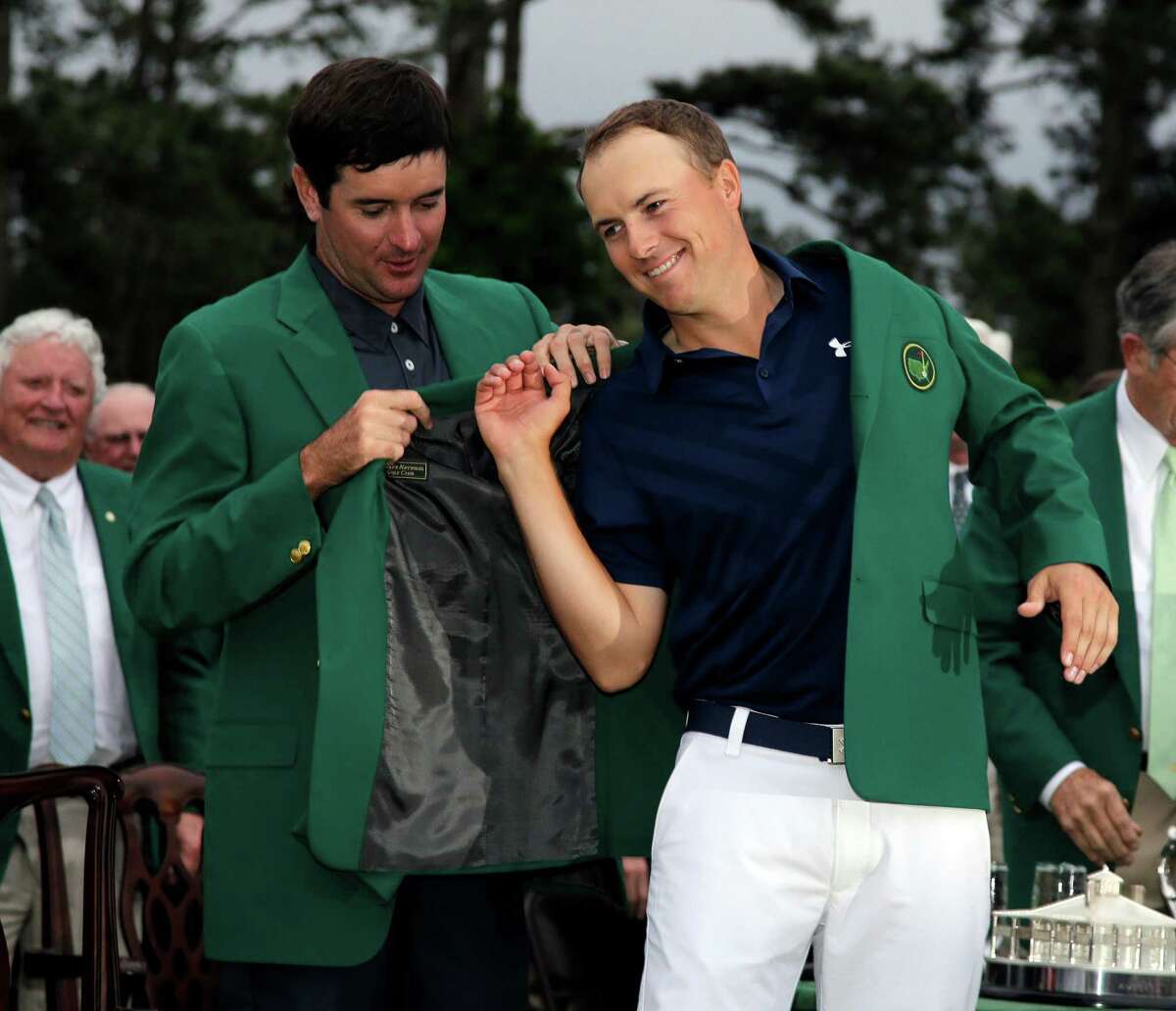 Bubba Watson, who won in 2014, gives Jordan Spieth a helping hand with the champion's traditional green jacket after the 21-year-old Texan became the Masters' first wire-to-wire winner since 1976 and tied the 72-hole scoring record of 18 under par.